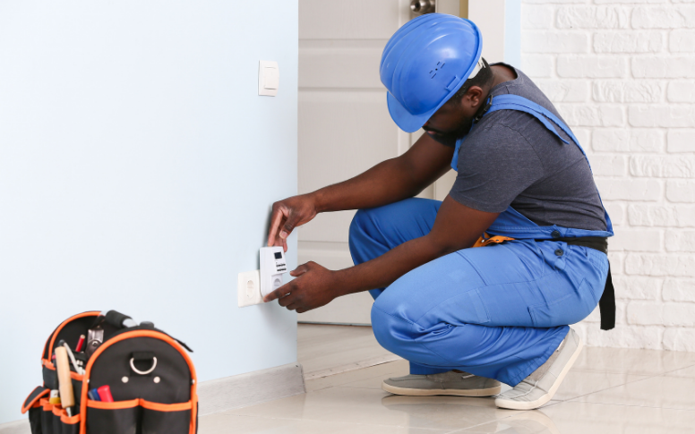 An electrician wears a blue hard hat and works in comfort, wearing a dungaree suit