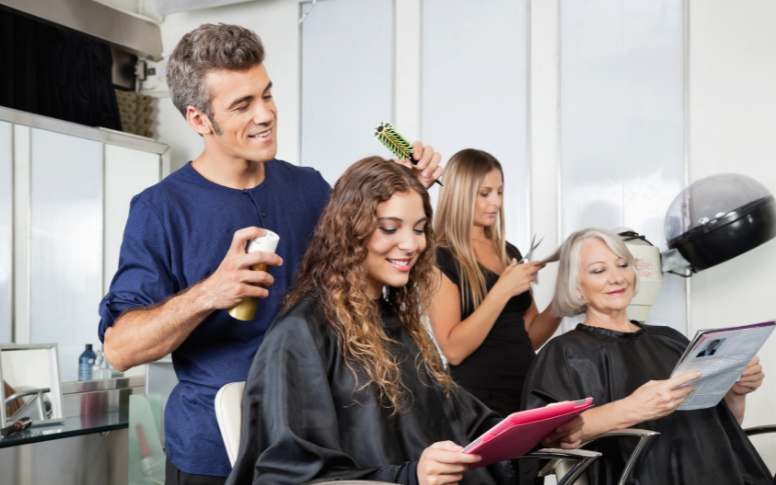 A beauty salon's staff wear uniforms and customers wear black hairdresser capes