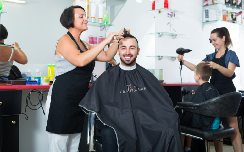 Clients at the salon wearing hairdresser's cape with the salon's logo on it