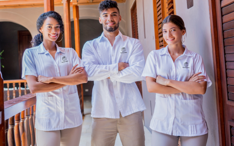 A group of three employees is showing off their salon's dress code by putting the salon's logo on their shirts